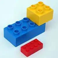 Duplo bricks alongside a smaller regular-sized Lego brick.