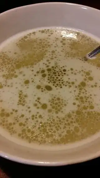 Foamy yellow broth in a bowl