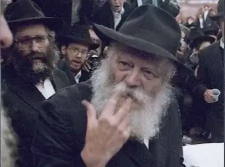 Lubavitcher Rebbe holding two fingers to his face, to signal whistling