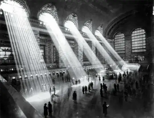 people in large hall lit up by rays of light from windows