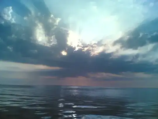 Sun behind clouds, taken with a cellphone camera through sunglasses