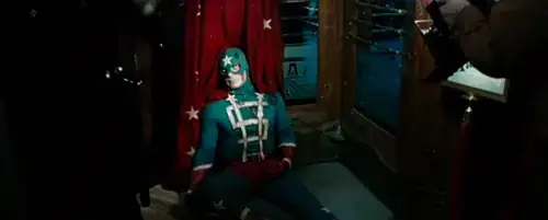 Astill from the film _Watchmen_, showing Dollar Bill, lying dead with his cape caught in a revolving door