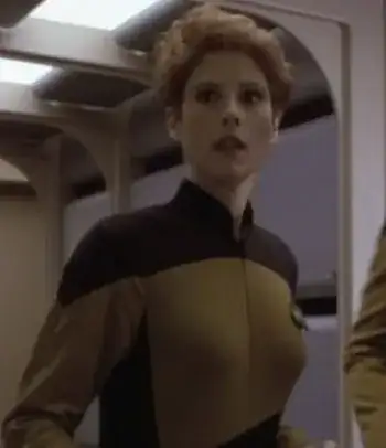 woman in a door frame, short red hair, yellow and black uniform