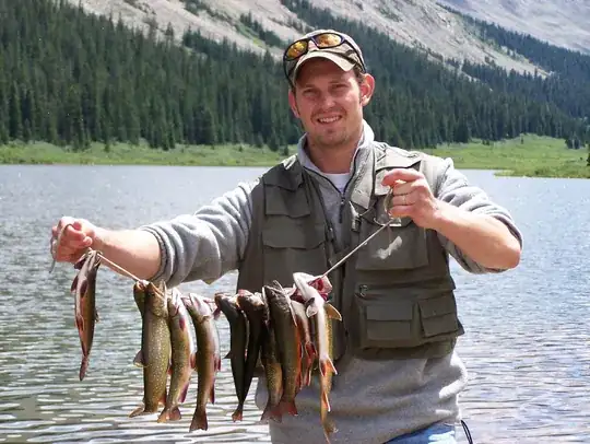 Fisherman holds 10 fish suspended from a string of cord