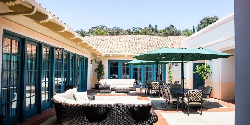 An outdoor courtyard with seating and a green umbrella.
