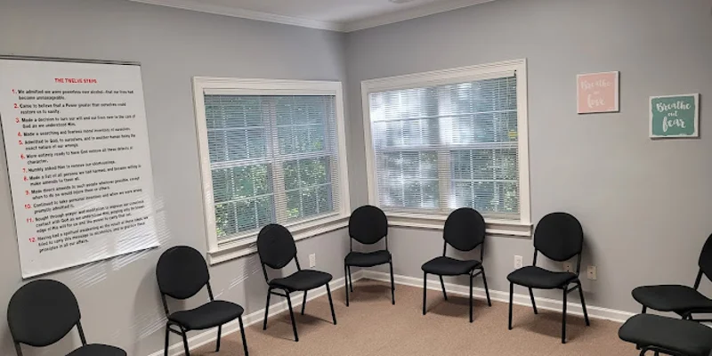 A group therapy room with black chairs arranged in a circle.