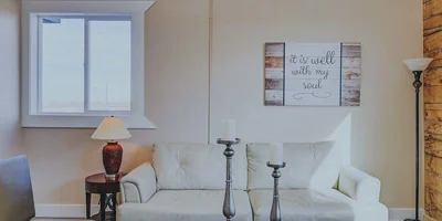Cozy lounge with a white couch, lamps, and framed wall art.
