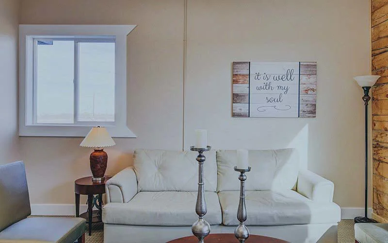 Cozy lounge with a white couch, lamps, and framed wall art.