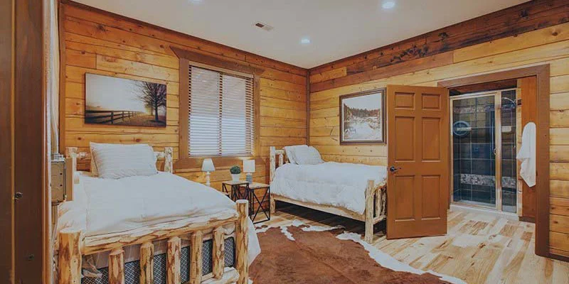 Rustic bedroom with wooden walls, two twin beds, and western decor.