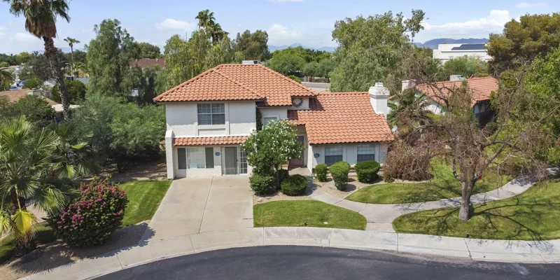 Two-story hoouse around greenery and a lawn.