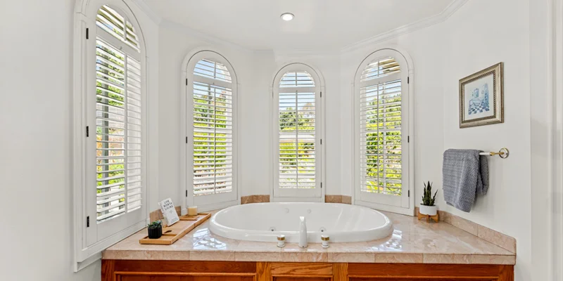 A bathroom with a large jacuzzi tub and arched windows.