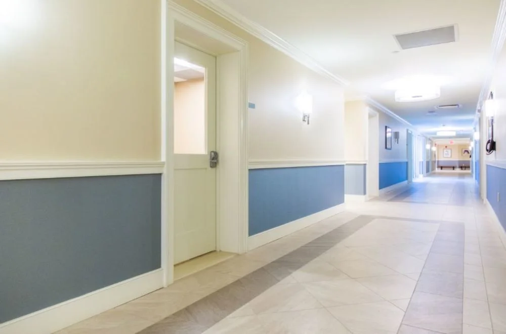 Long hallway with artwork, doors, and directional signs.