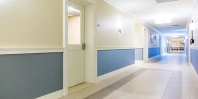 Long hallway with artwork, doors, and directional signs.