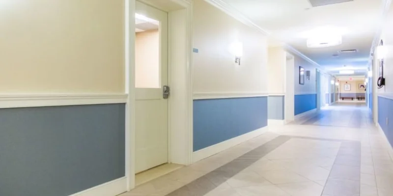 Long hallway with artwork, doors, and directional signs.