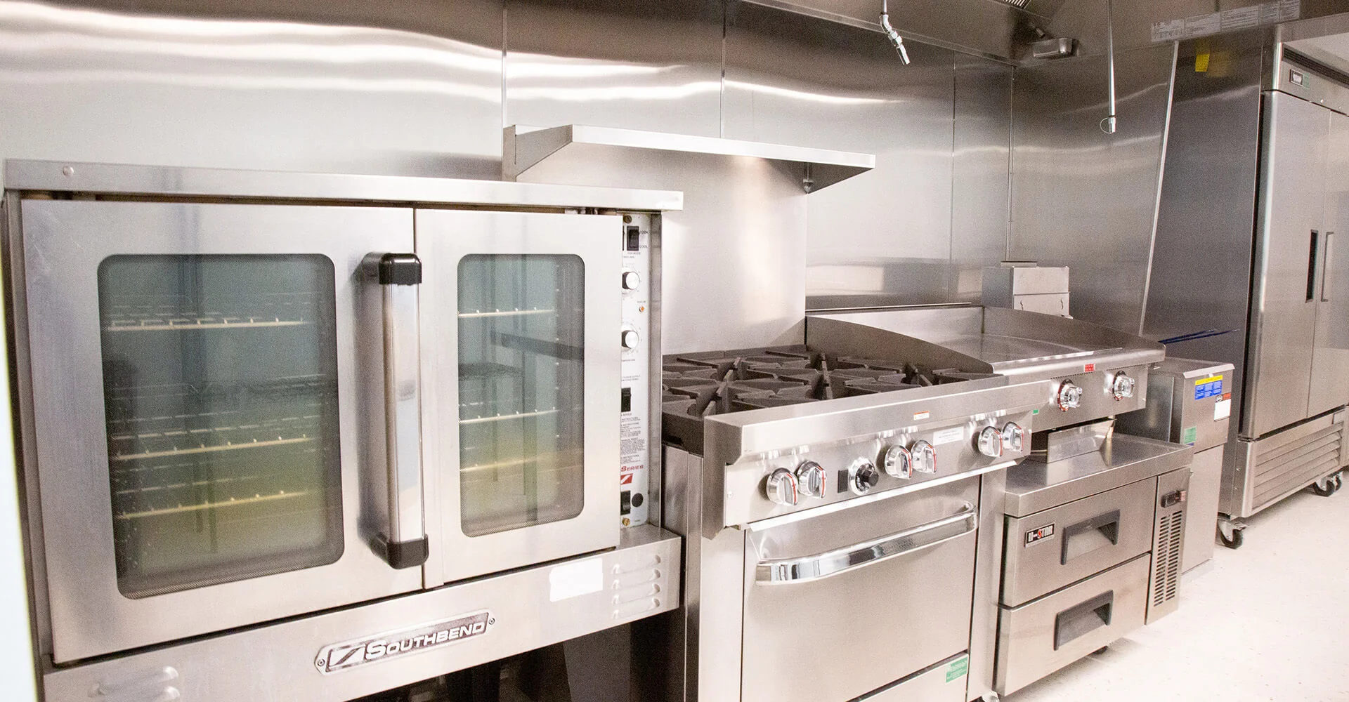 Kitchen with a large oven, stove, and refrigerators.