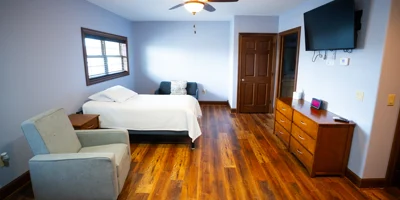 Spacious bedroom with TV, dresser, and armchair