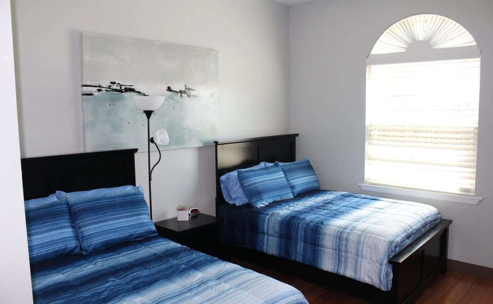 Bedroom with two  beds, a large window and wall art.