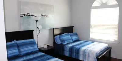 Bedroom with two  beds, a large window and wall art.
