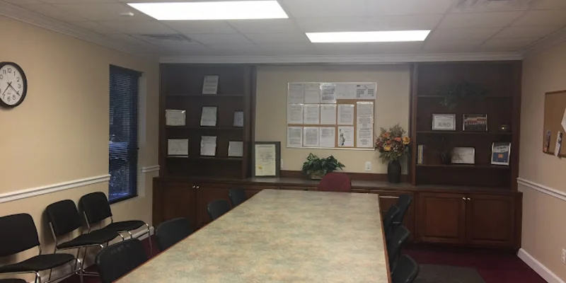 A meeting room with a large table, chairs, and bulletin boards on the wall.