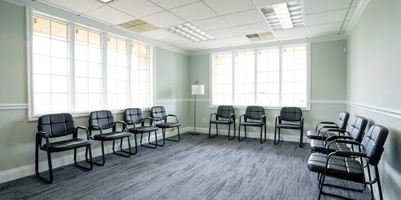 Spacious meeting room with black chairs and large windows.