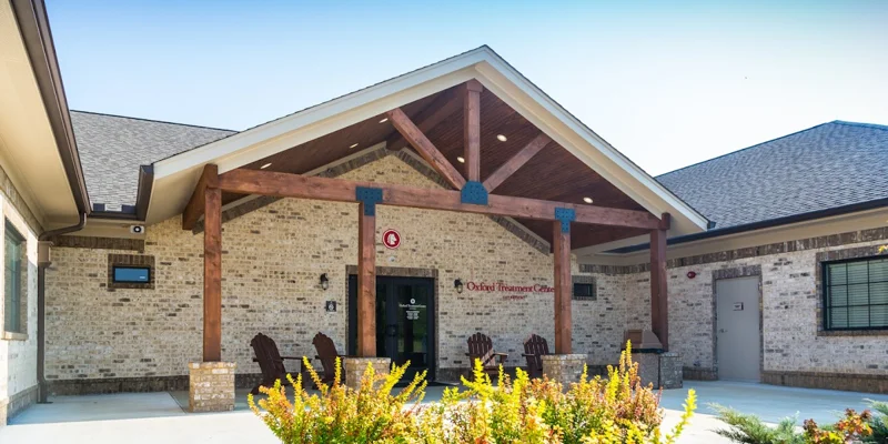 Brick rehab facility entrance with wooden beams and outdoor seating.