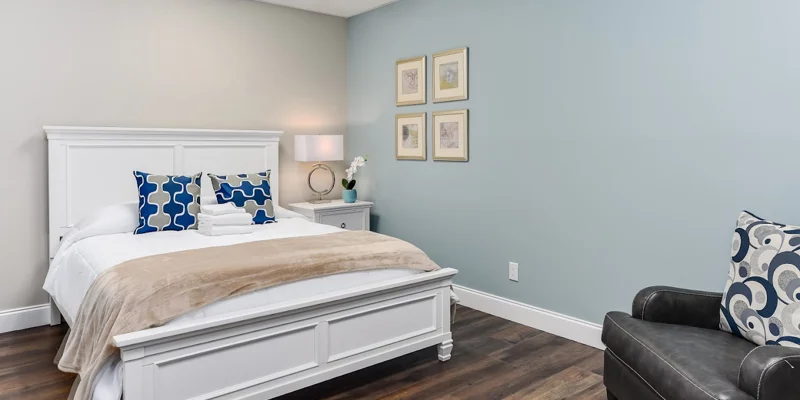 Bedroom with white bed, armchair, and soft lighting