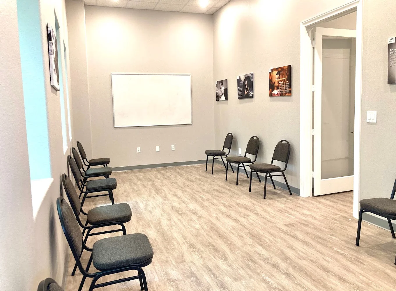 A bright group therapy room with chairs facing a whiteboard.