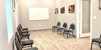 A bright group therapy room with chairs facing a whiteboard.