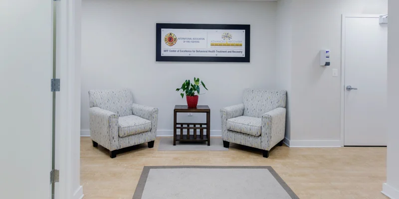 Cozy waiting room with two chairs and a potted plant.