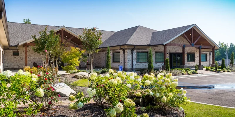 Exterior of a brick rehab facility with landscaped flowers and greenery.