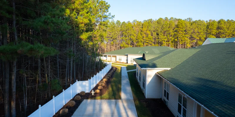 Pathway between rehab buildings next to tall pine trees