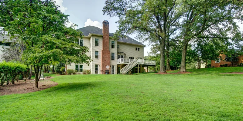 A rehab facility’s backyard with lush green lawn and mature trees