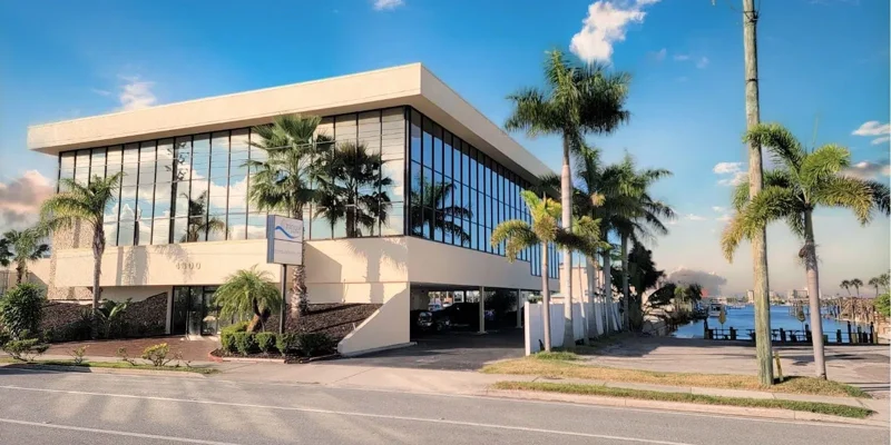 Exterior of Facilit with glass windows, surrounded by palm trees.