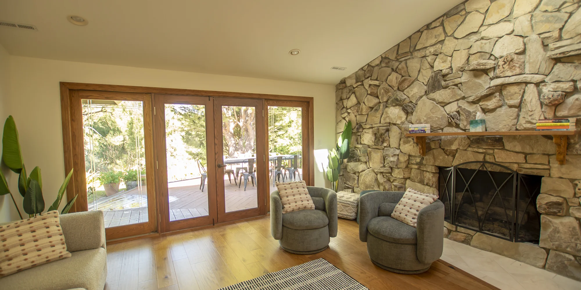 A cozy sitting area with a stone fireplace and outdoor deck access.