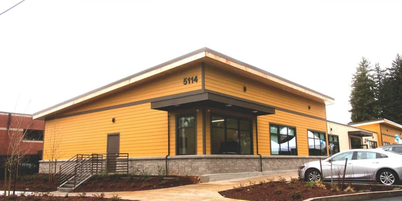 Building exterior with large windows and parking next to entrance.