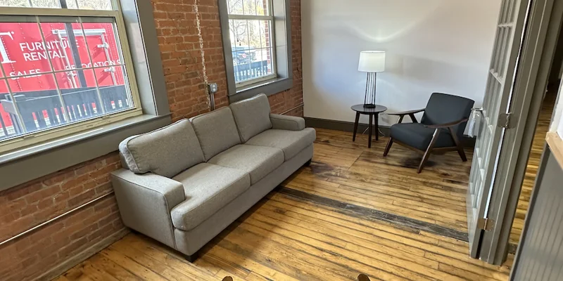 Private seating nook with gray sofa, chair, and natural light