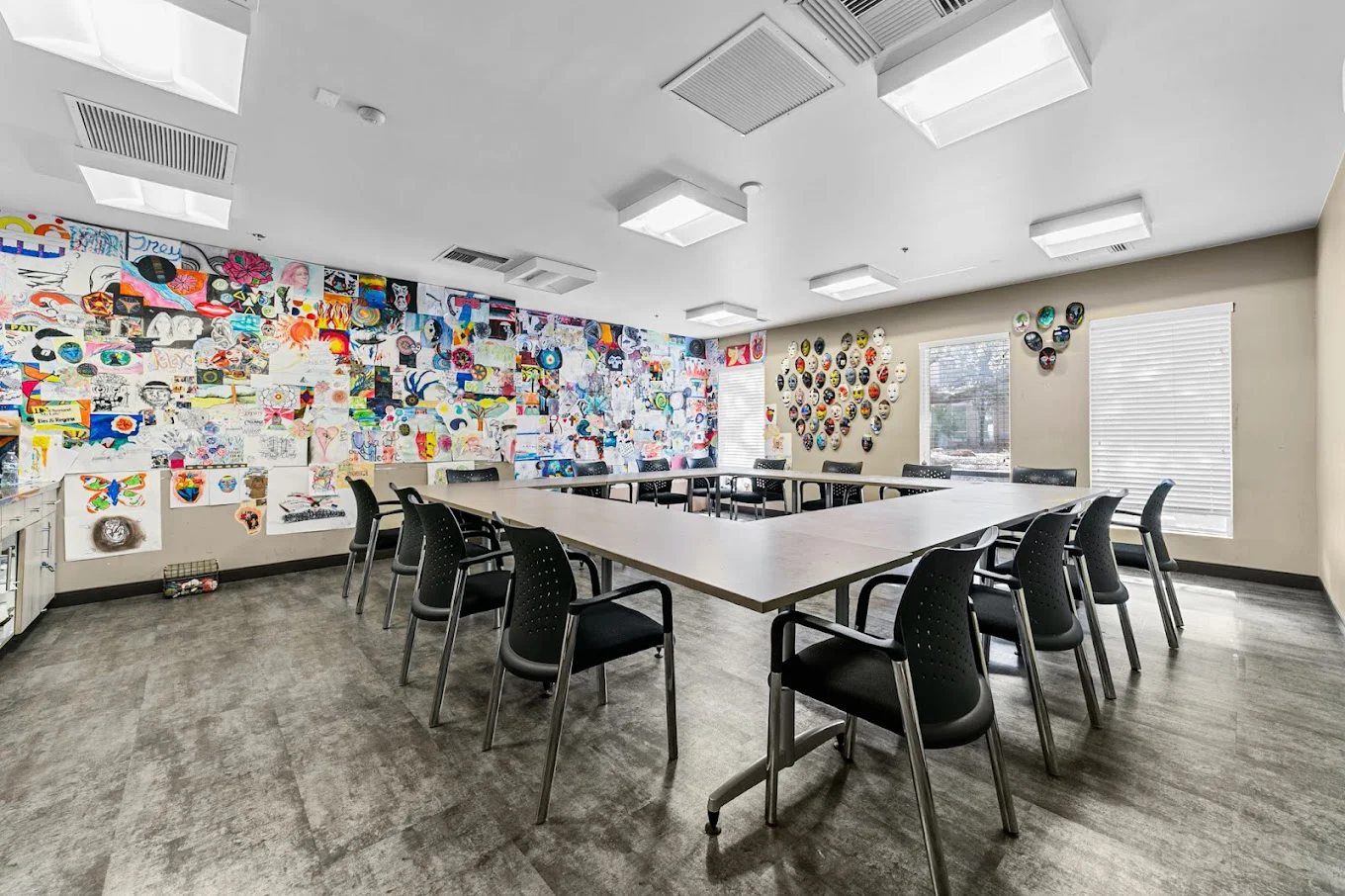 A rehab therapy room with tables and colorful wall art.