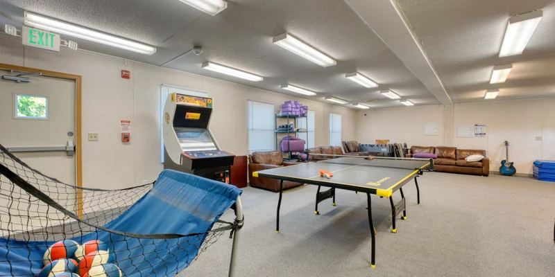 Recreation room with ping pong, arcade, and couches.