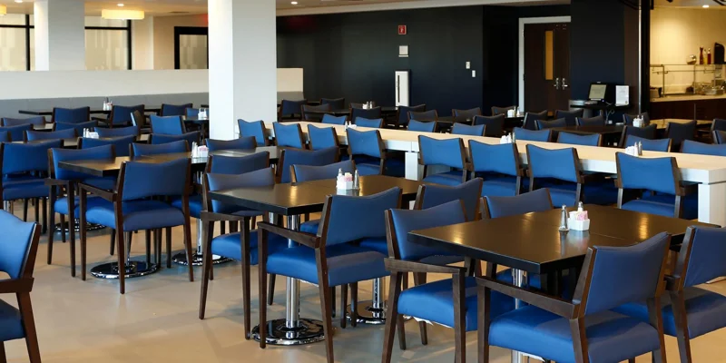 Modern dining area with blue chairs and black tables.