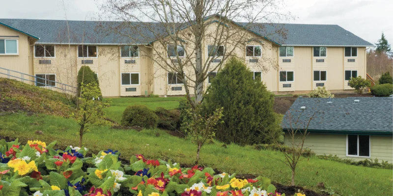 A large rehab facility with gardens and a landscaped front yard.