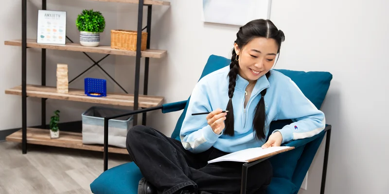 Individual seated in therapy room with wall art and decor.