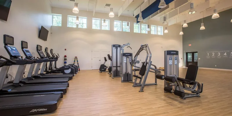 Fitness center with treadmills, weight machines, and bright lighting