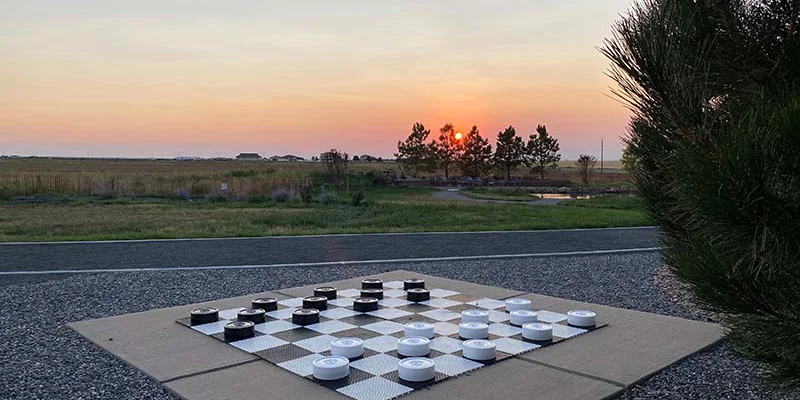 Outdoor checkerboard game with a sunset over open fields.