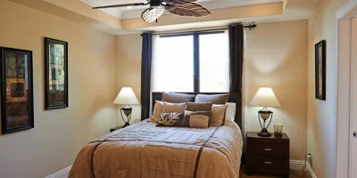 Warm bedroom with a ceiling fan and bedside lamps.