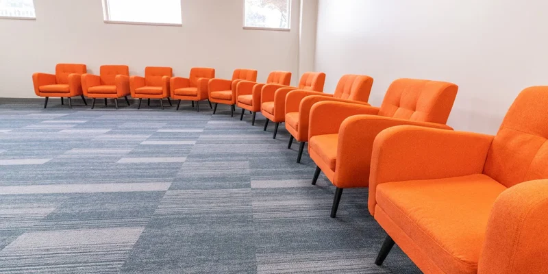 Group therapy room with orange chairs arranged in a semi-circle.
