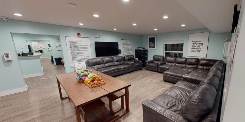 Group lounge with large sofas, fruit on table, and wall posters.