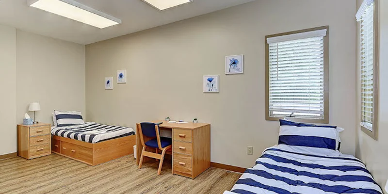 Shared bedroom with two striped twin beds and a wooden desk.