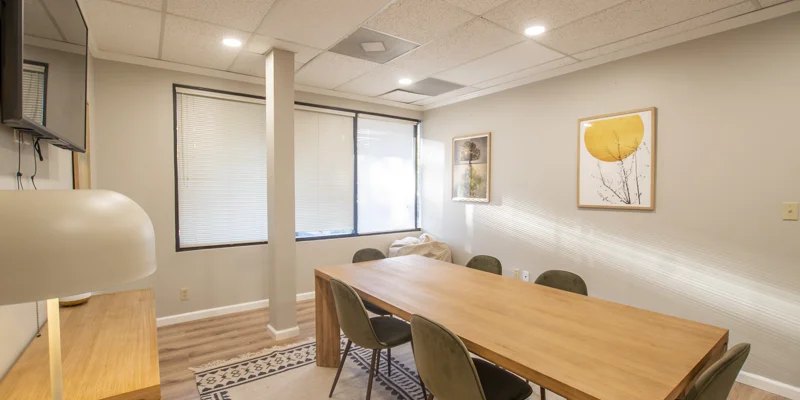 A small meeting room with a wooden table and modern artwork.