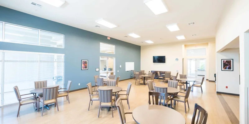 Dining area with round tables, a TV and large windows.