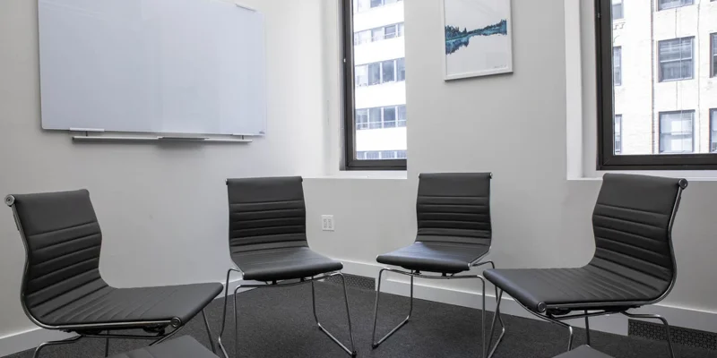 Group therapy room with black chairs.